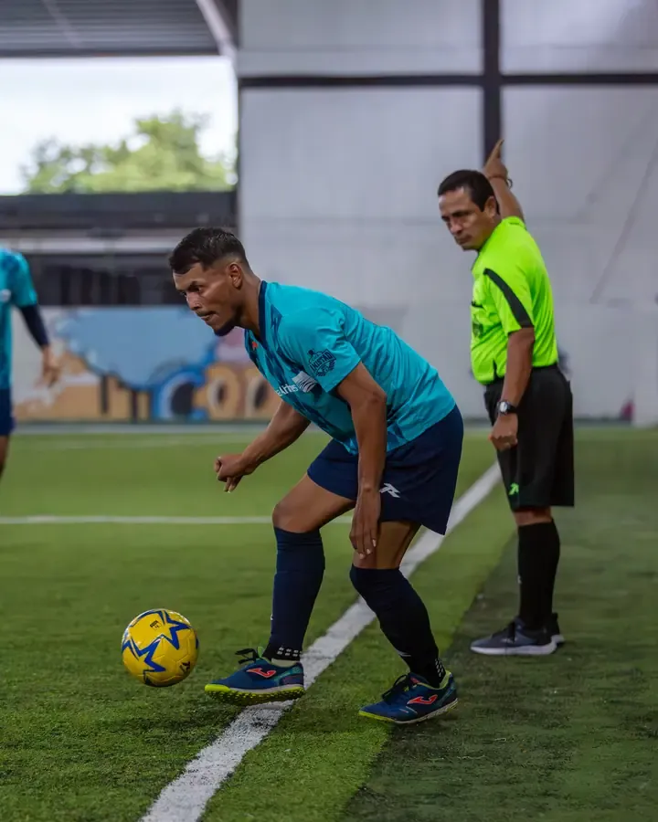 Jugador controlando el balón junto al árbitro